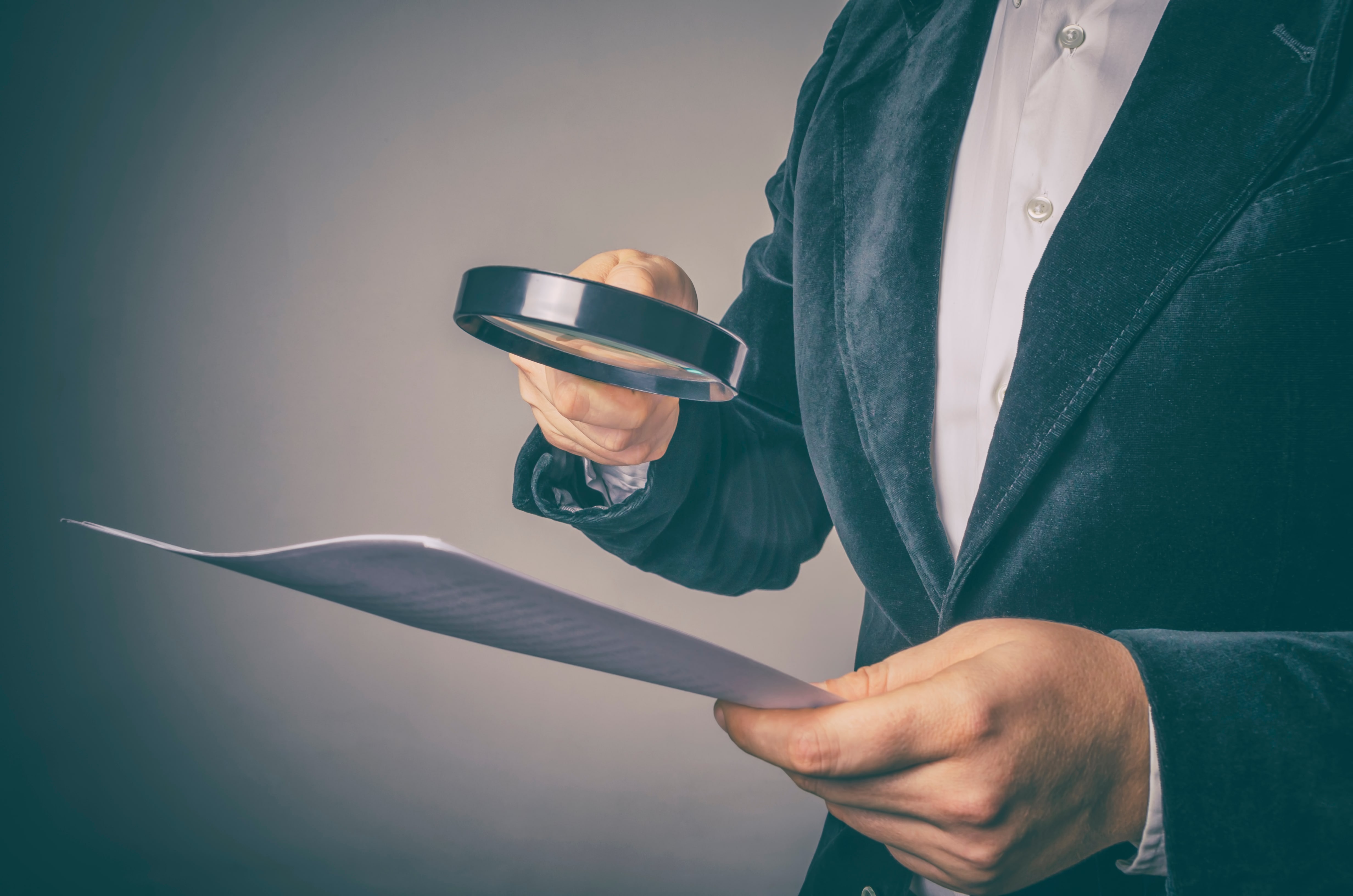 persona analizando papel con lupa